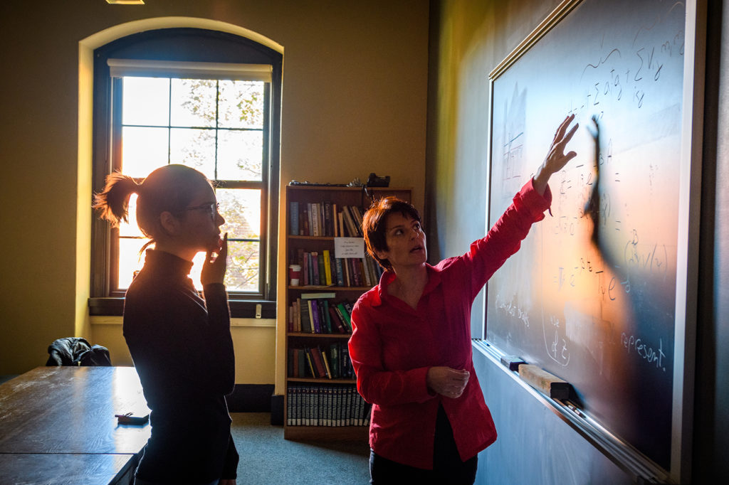 Liana-Shpani works with Physics Professor Barbara Sansone at the blackboard