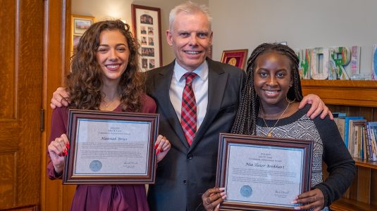 President David Angel presents Lund awards to Hannah Brier ’20, left, and Nia Slater-Bookhart ’19.