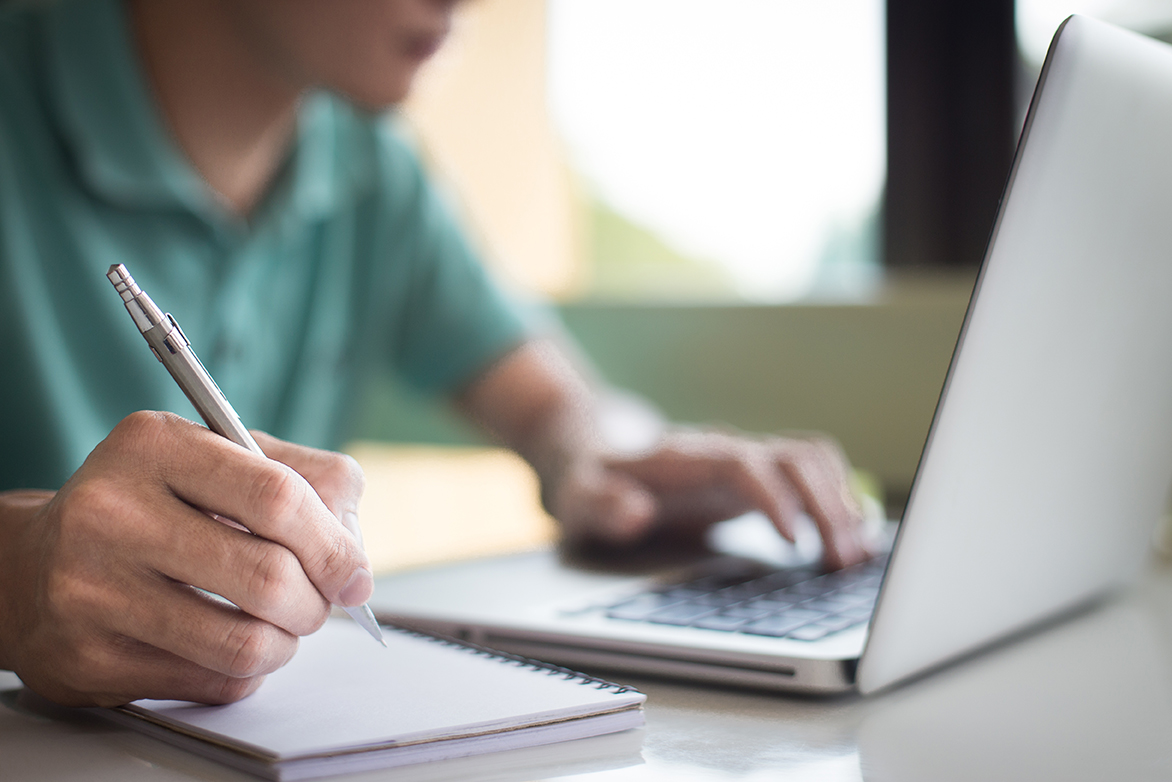 Person on laptop with notebook