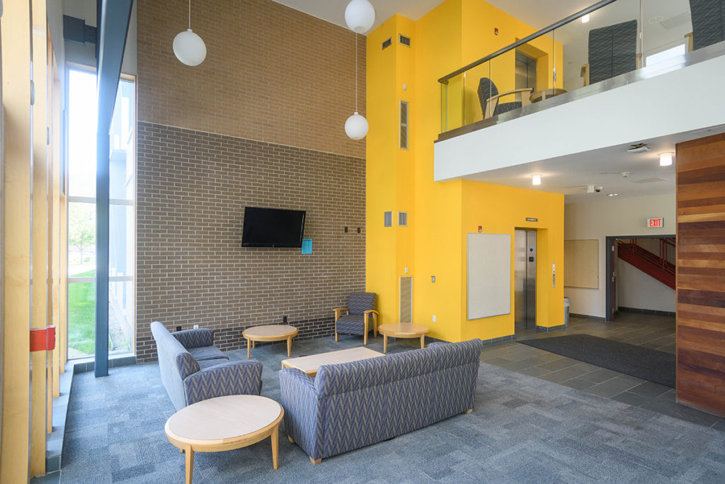 A residence hall common area with chairs and a couch at Clark University