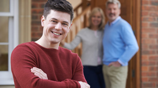 Young man outside house with parents