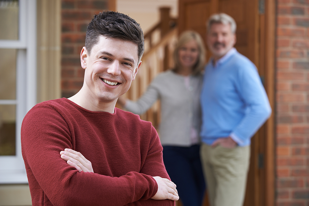 Young man outside house with parents