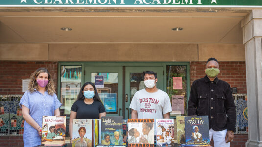 University Park Campus School teacher (and Clark alumna) Helen Ward, Claremont Academy junior Ailany Rivas, UPCS senior Fernando Matos, and Clark professor Raphael Rogers outside the Claremont Academy with some of the books they used in their research on how slavery is represented in schools and children’s book publishing.