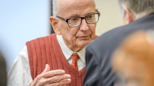 William Koelsch, M.A. ’59, speaks with an attendee of 