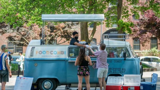 students serve food from a Volkswagen food tru