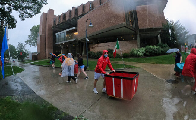 Clark University students on Move-In Day. One student pushes a moving bin.