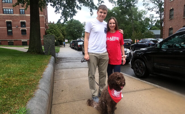 Clark University student and his mother pose with their dog.