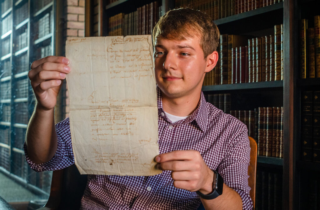 Dillon Prus holds historic Belgian letter found in the Clark University archives.