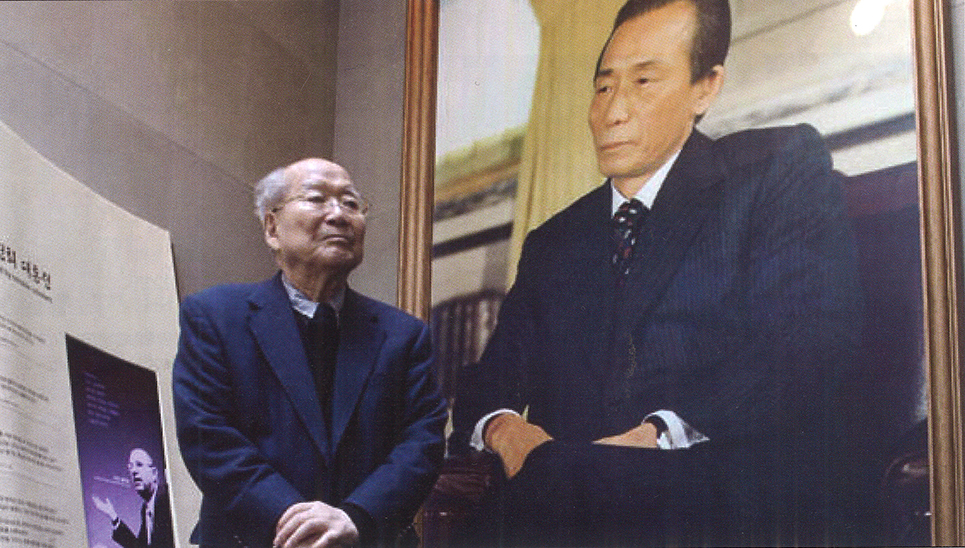 Kim Chung-yum, M.A. ’59, LL.D. ’95, stands with a portrait of former South Korean President Park Chung Hee at the opening of the Park Chung Hee Memorial-Library in 2012