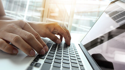 Unidentified person works at a laptop