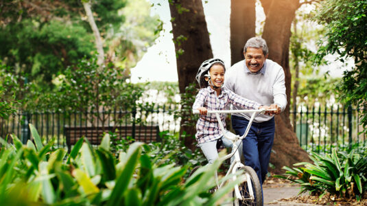 Grandfather pushing granddaughter on bike