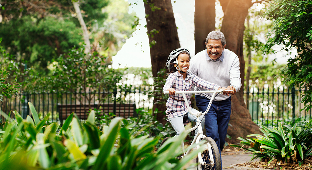 Grandfather pushing granddaughter on bike