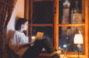 Woman sitting in large window using a laptop