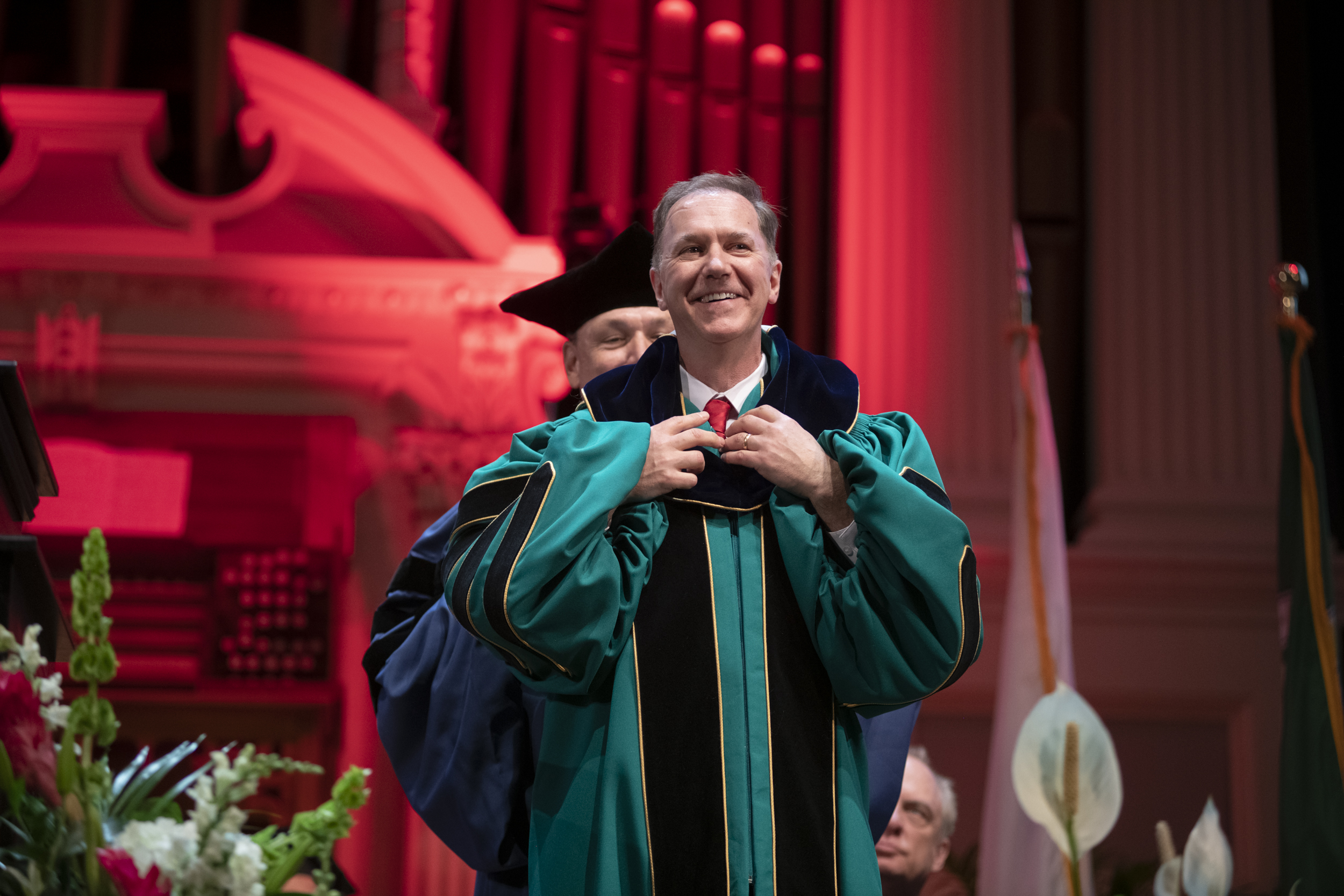 Michael Rodriguez stands behind David Fithian on stage during the investiture ceremony. 