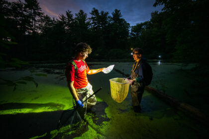 two students wade into pond