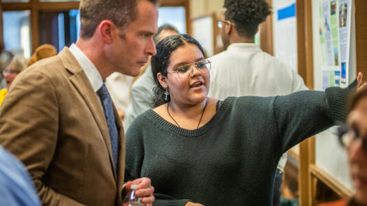 Student talking to faculty member about poster