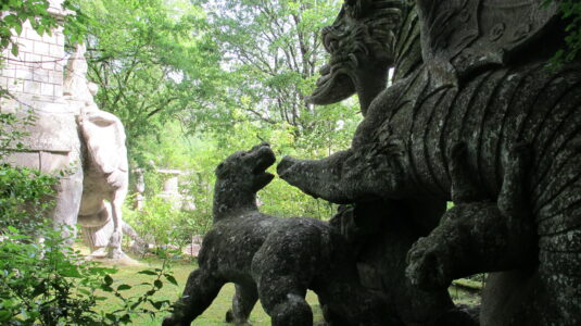 A sculpture of a dragon fighting with lions in Bomarzo, Italy