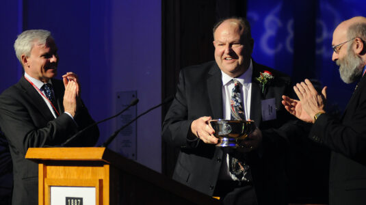 Allen Glick (center) is presented with the Distinguished Alumni Award by then-President David Angel (left) and Professor Everett Fox.