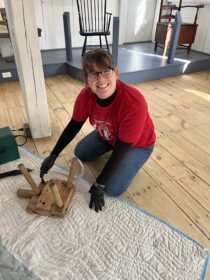 Maire O'Donnell ’23 vacuums a historic stool at Old Sturbridge Village. 