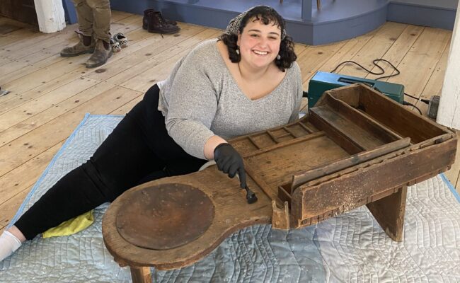 Hannah Friend ’23, M.A. ’24, with a historic bench at Old Sturbridge Village.