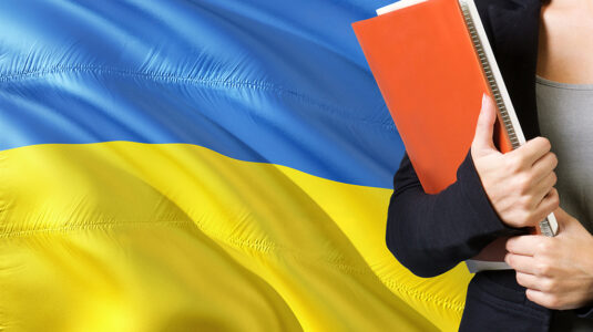 Student with books in front of Ukraine flag