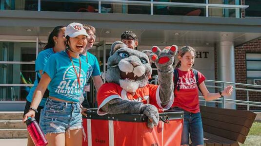 the cougar mascot posing with students