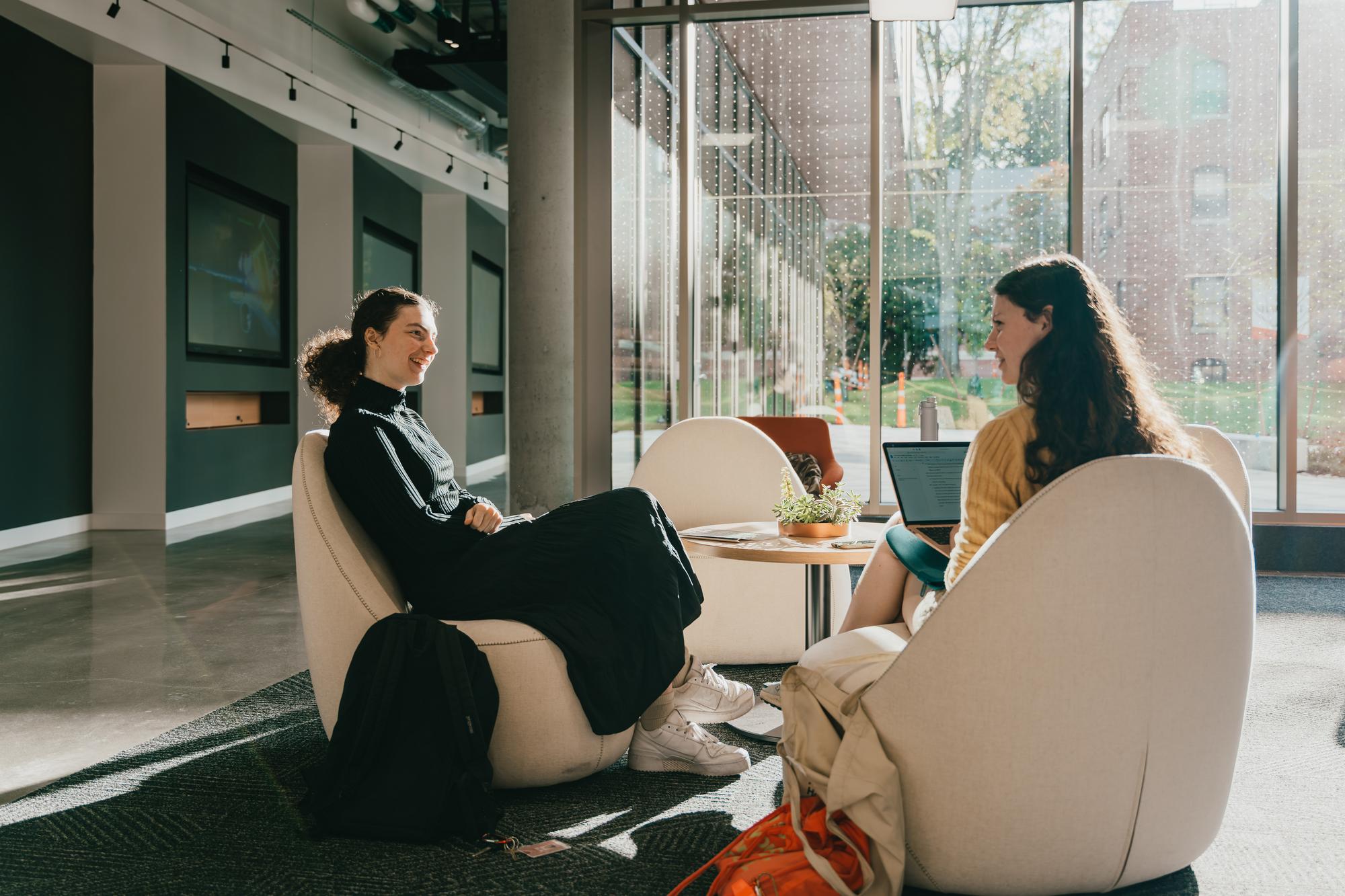 Two students sitting in chairs talking