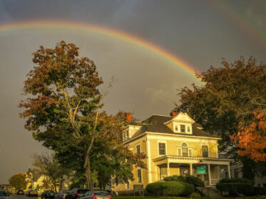 a rainbow over yellow house