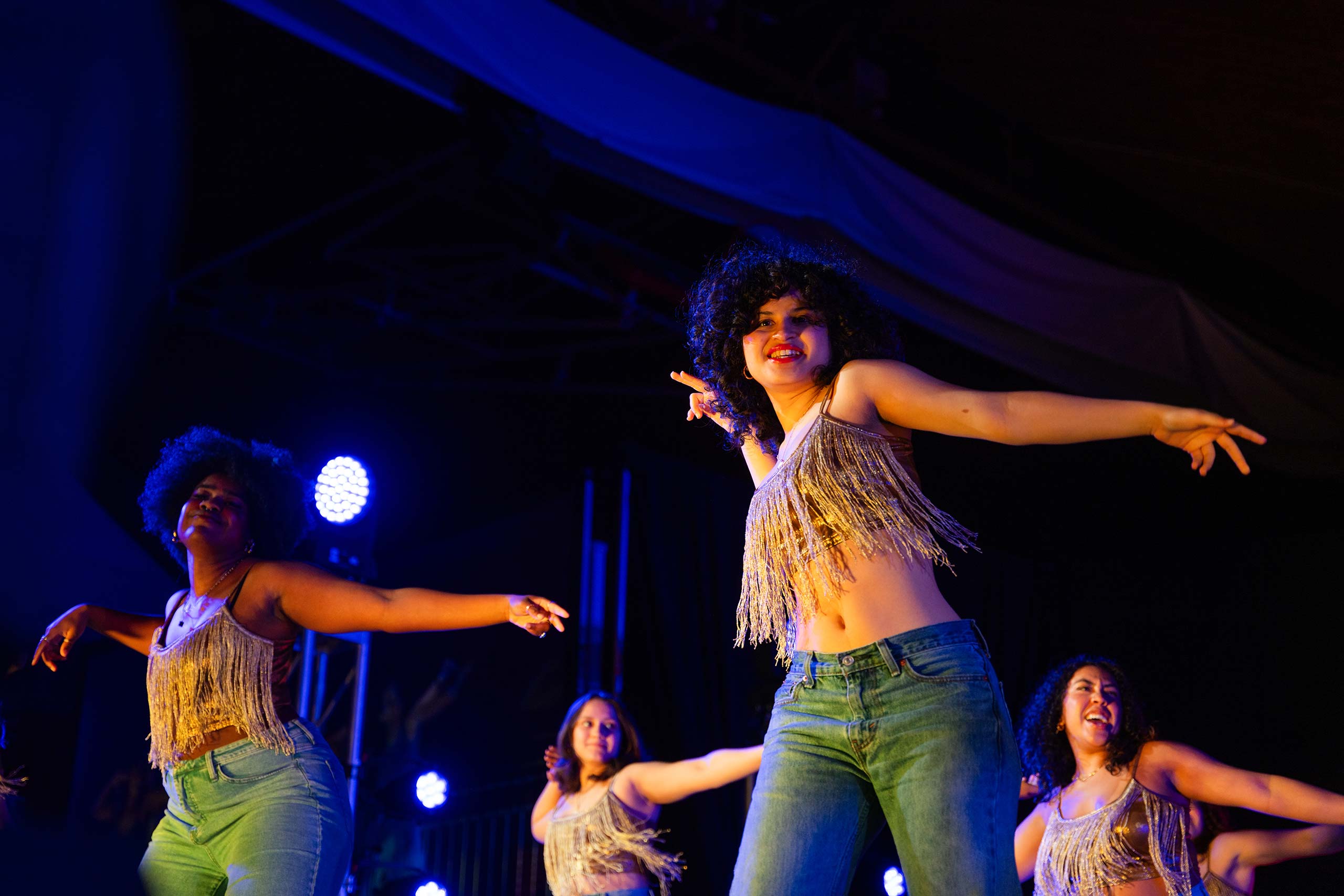 Students wearing beaded tops hold their arms outstretched during a dance performance at the 2024 Gala event