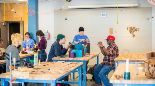 students and professor around workbench