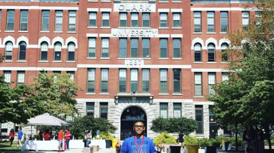 Student poses in front of brick building