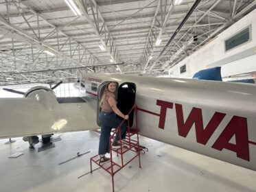 person walking onto airplane in hangar