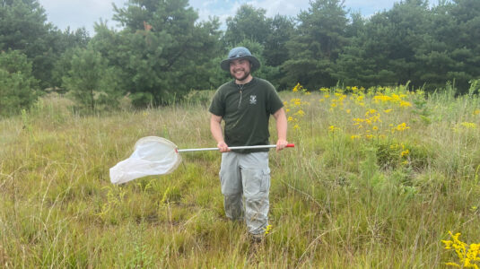 man in field with butterfly net