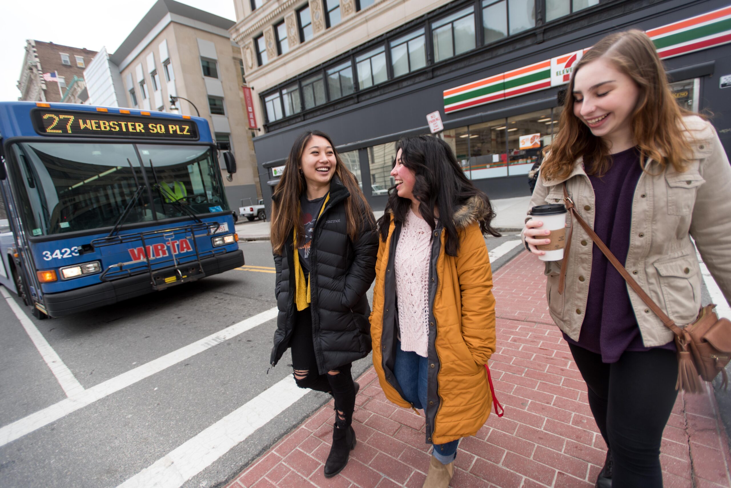 students walk in crosswalk in front of blue city bus