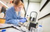 student wearing blue works in lab