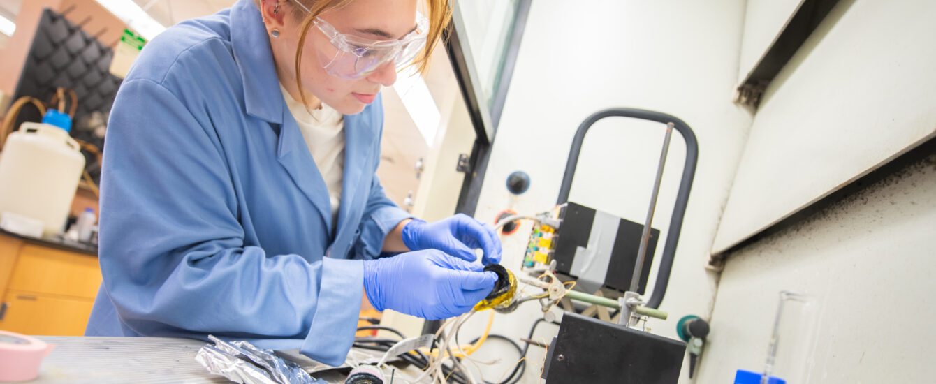 student wearing blue works in lab