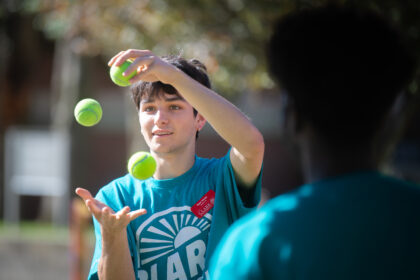 student juggling tennis balls