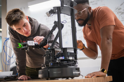 two students work on robot in lab