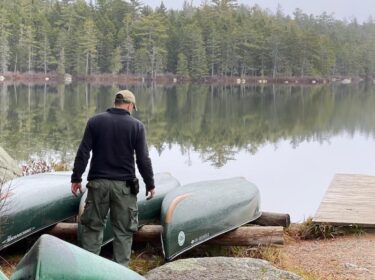 man looks at canoes on shore