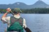 man padding canoe on lake surrounded by mountains