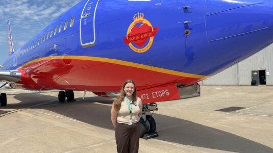 woman standing in front of blue airplane