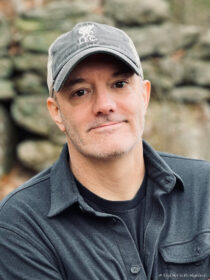 headshot of man wearing baseball cap