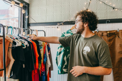 student looks through rack of shirts