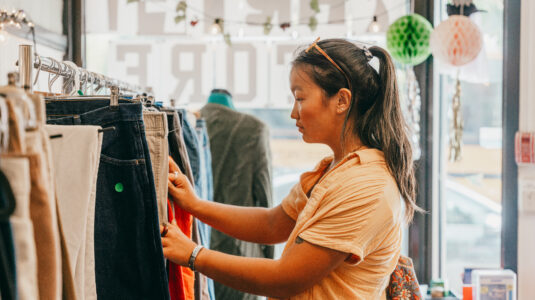 student looks through rack of pants