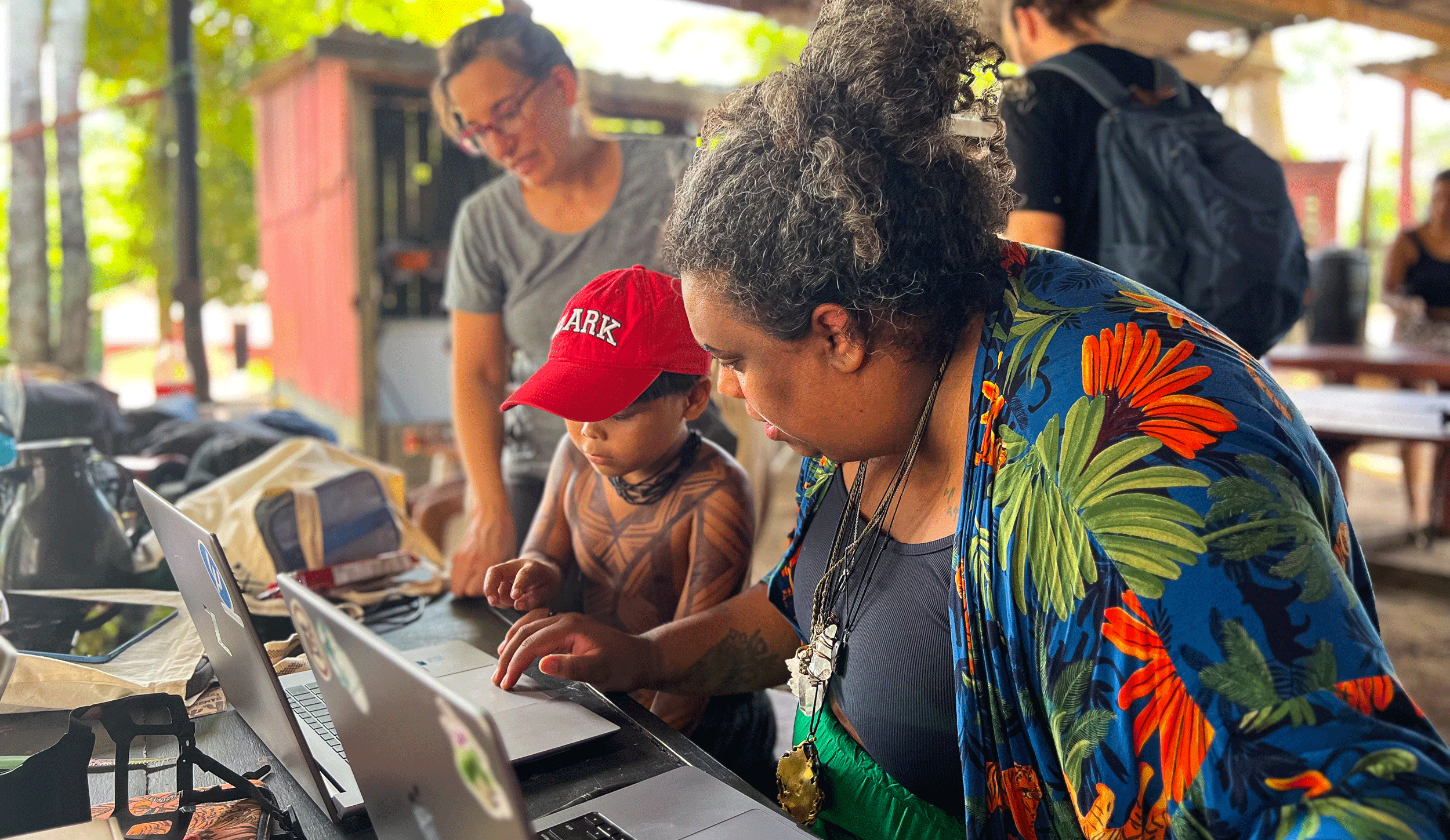 Florencia Sangermano and a child and adult from a local community working on a computer