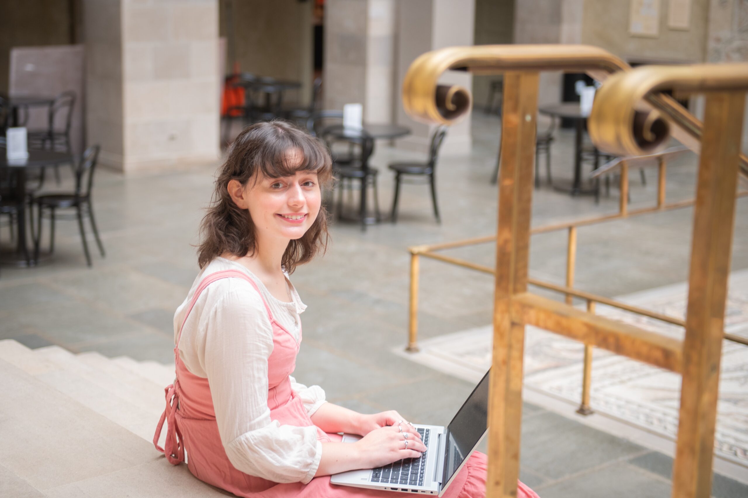 student sitting on museum steps with laptop