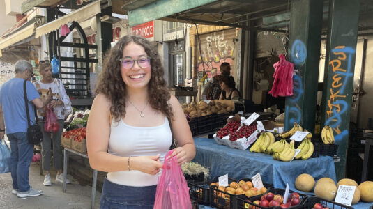 Student holding bag of cherries at a fruit stand