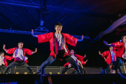 people dance on stage in red robes