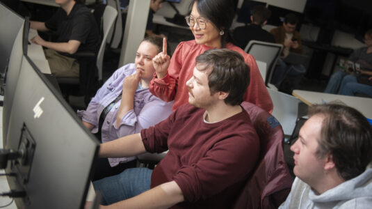 professor works with students at computers