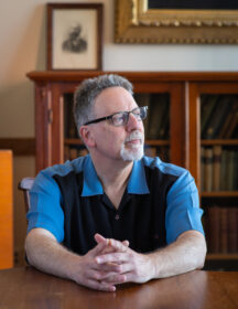 Professor sitting at table looking out window